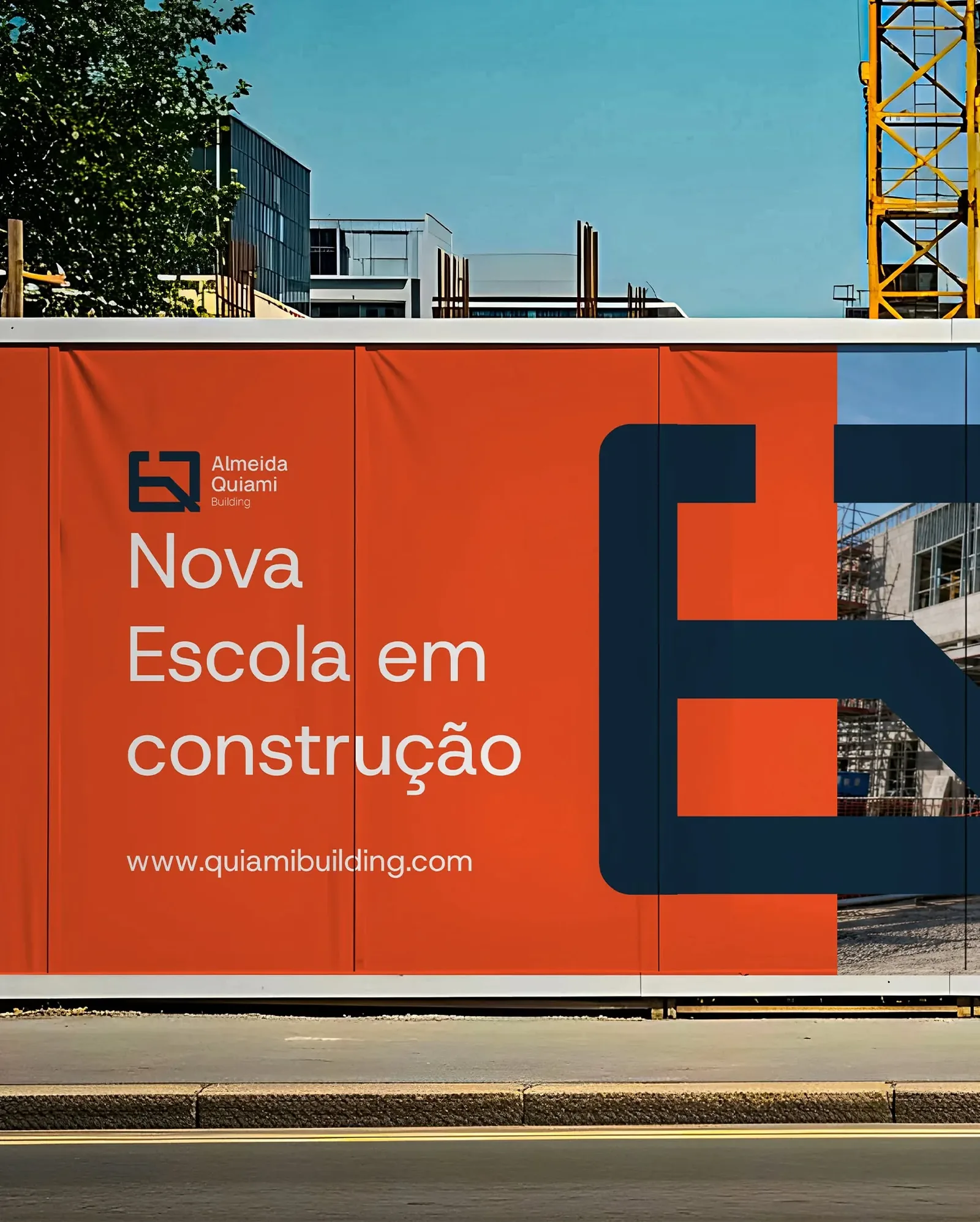 Almeida Quiami construction hoarding — Nova Escola em construção announcement in white on orange, with the giant navy monogram over a site photo