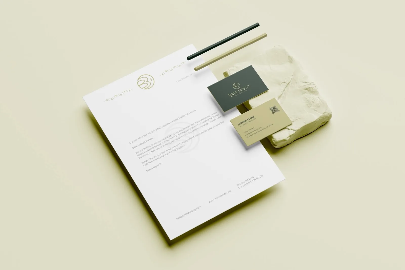 Mira Beauty stationery system — letterhead with gold monogram watermark, forest-green and chartreuse business cards on a plaster block