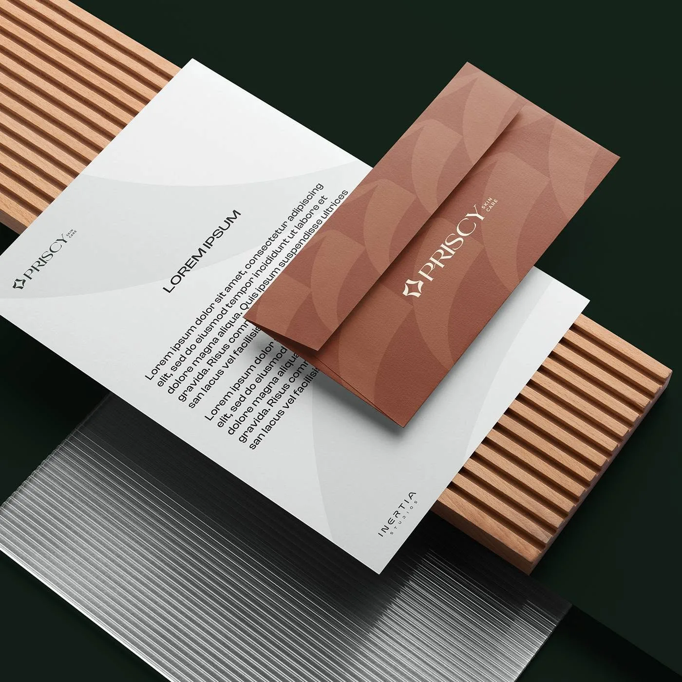 Priscy stationery system — letterhead and terracotta envelope with the petal pattern on wooden slats