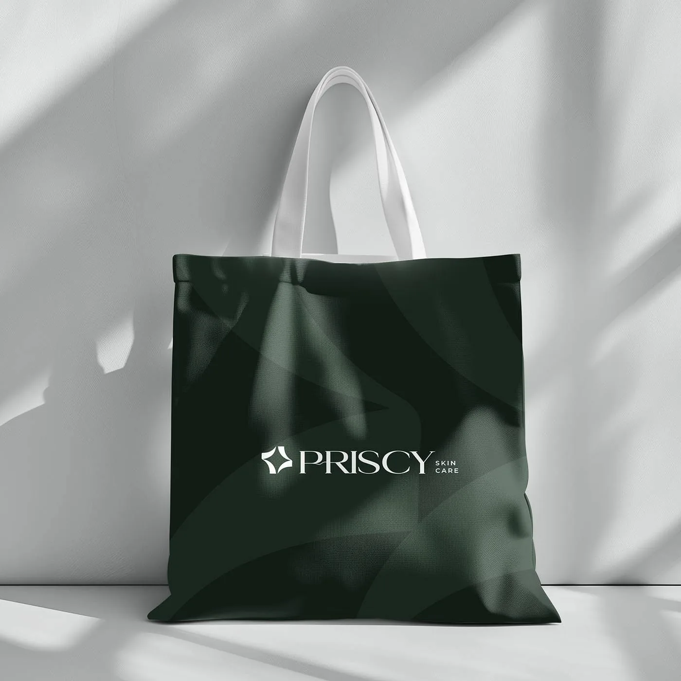Priscy tote bag — cream lockup on a forest-green bag printed with the petal pattern