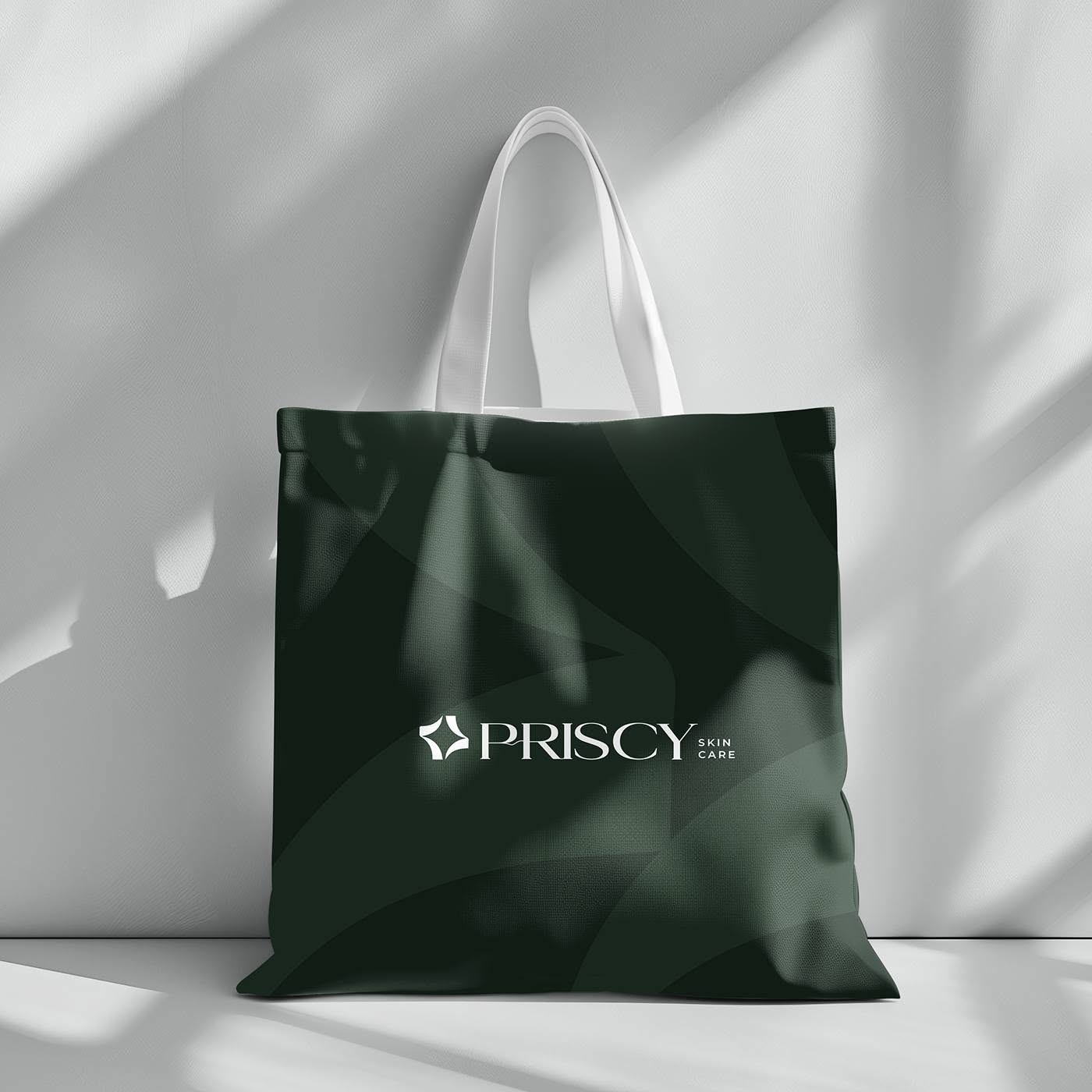 Priscy tote bag — cream lockup on a forest-green bag printed with the petal pattern