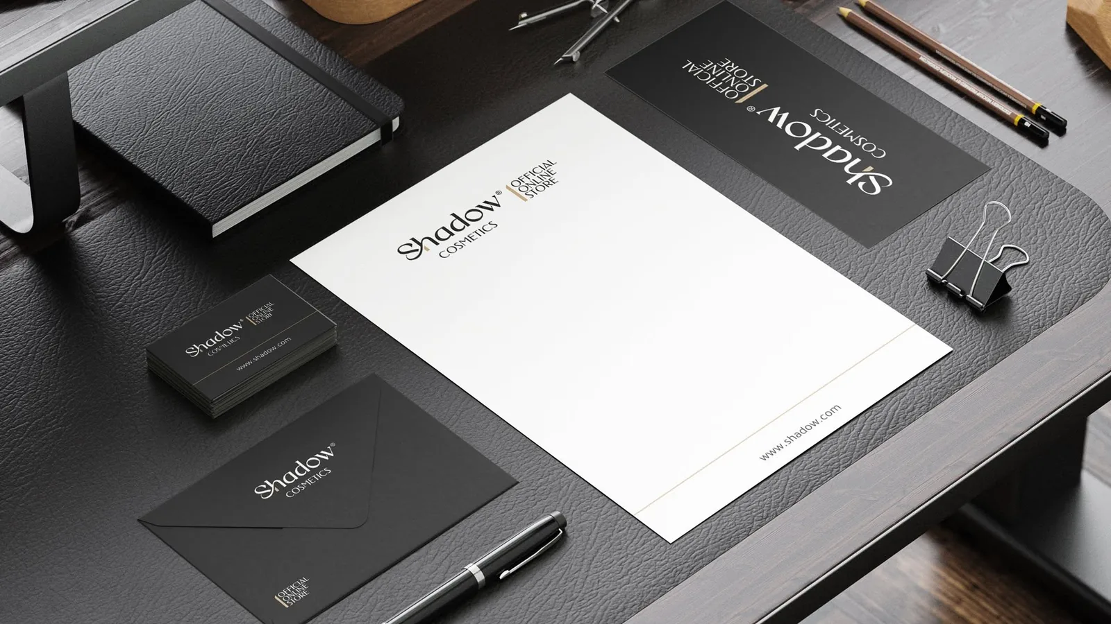 Shadow Cosmetics stationery system — letterhead, business cards, black envelope and brand cards on a desk